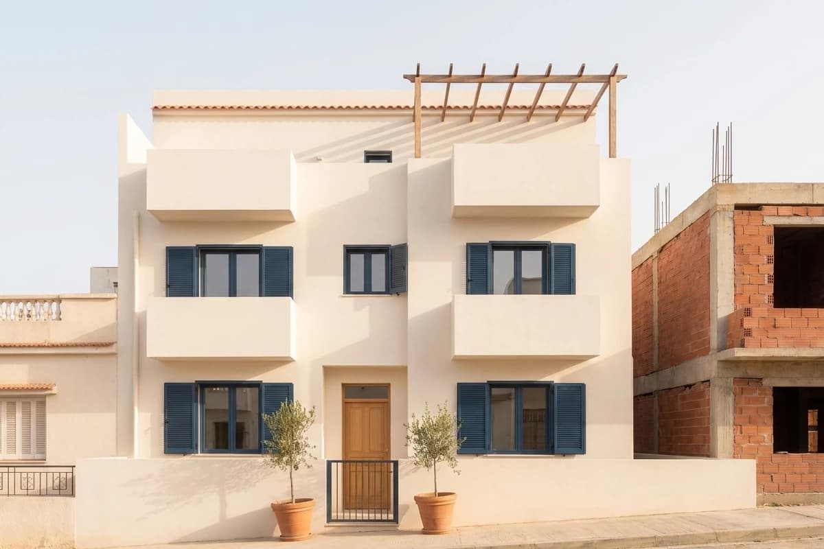 La maison des Mebarki terminée : façades blanches, volets bleus, terrasse.