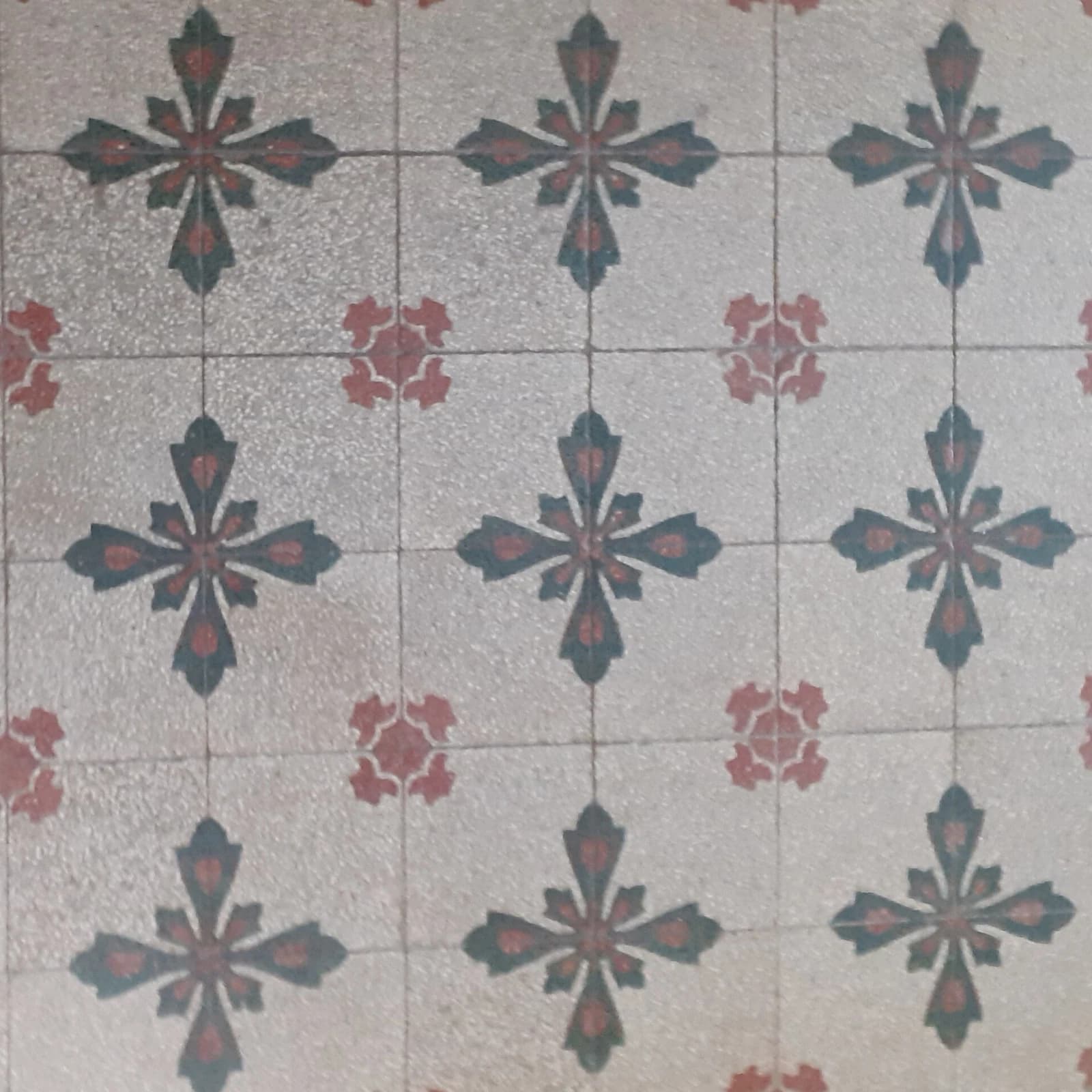Un sol de carreaux de ciment anciens, motifs sang-de-bœuf et vert sombre.