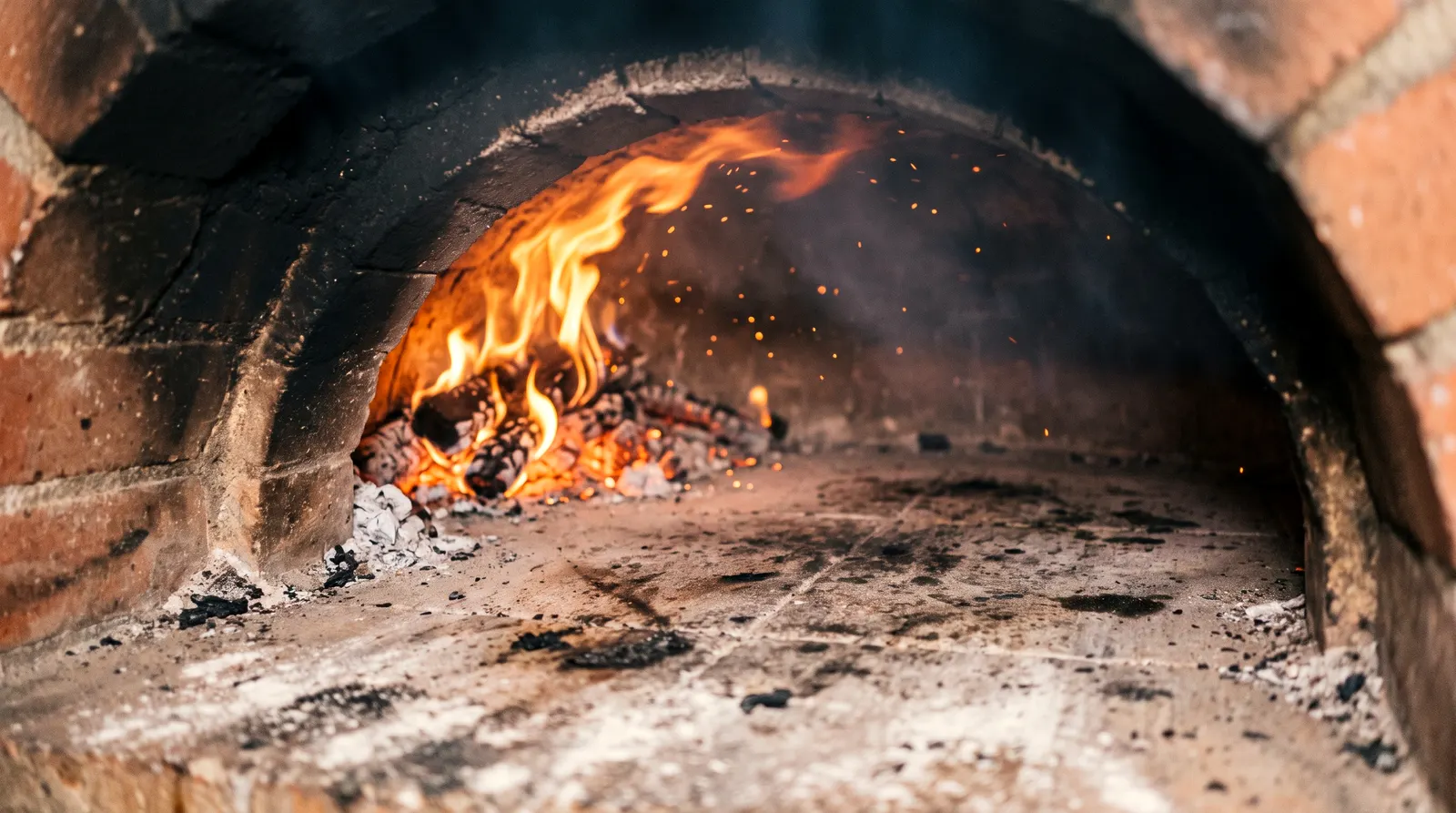 Le dôme en briques du four, la bouche éclairée par le feu